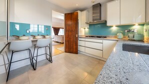 Une cuisine moderne avec des armoires blanches, un comptoir en granit et une porte en bois.
