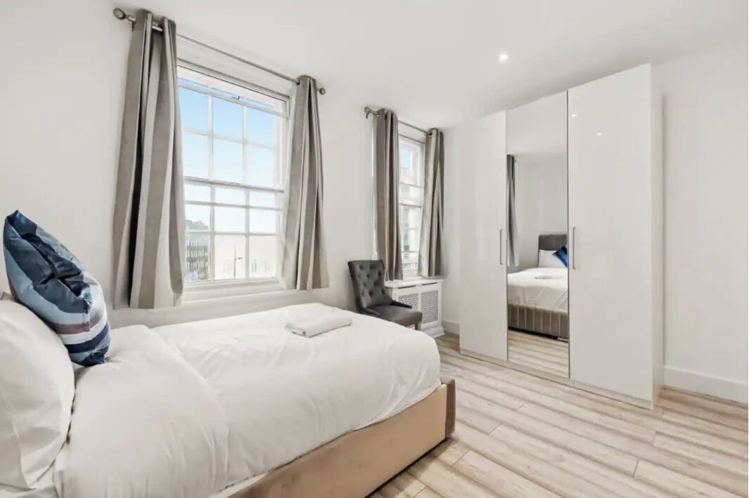 Un dormitorio con cama, una silla, un radiador y un armario.