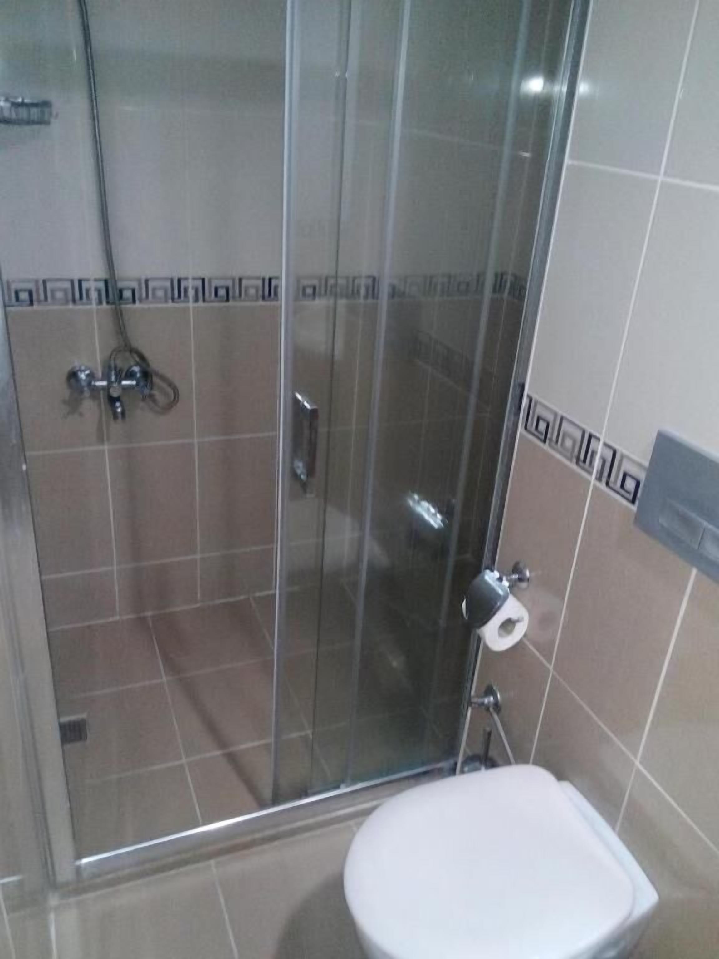 A bathroom with a glass-enclosed shower, a toilet, and a sink.