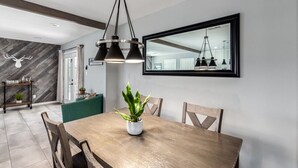 Un coin repas avec une table en bois, des chaises, une plante en pot et un luminaire suspendu moderne.