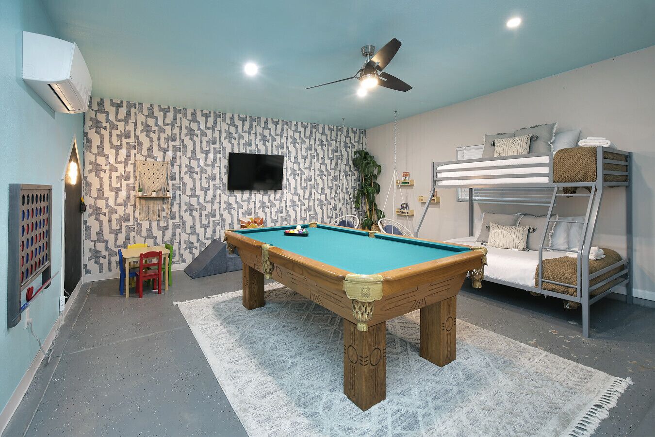 A room with a pool table, bunk beds, a ceiling fan, and a TV on the wall.