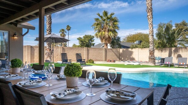 Un espace de restauration en plein air, avec des tables dressées pour le repas, donnant sur une piscine et des palmiers.
