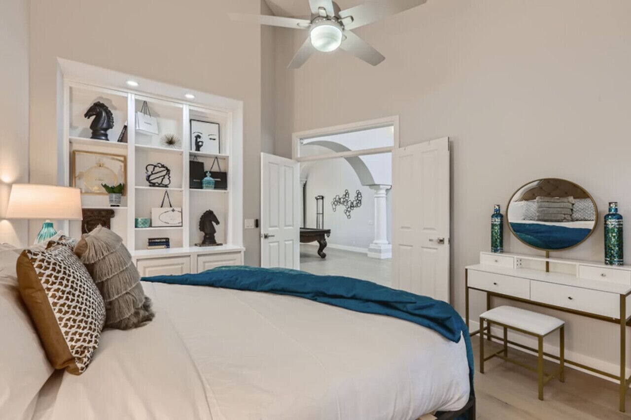 A bedroom with a bed, a nightstand, a dresser, a mirror, and a ceiling fan.