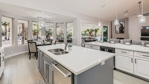 A modern kitchen with a large island, white cabinetry, and pendant lighting. - Resort Style Estate, 2 Houses, Putt-Putt Course, B-ball Court, Heated Pool (Scottsdale)