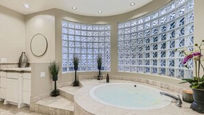 A spa area with a large bathtub, a decorative glass wall, and a small sink. - Resort Style Estate, 2 Houses, Putt-Putt Course, B-ball Court, Heated Pool (Scottsdale)