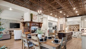 Uma cozinha ampla com uma ilha grande, armários de madeira e uma parede decorada com tijolos.