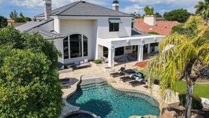 Uma casa com piscina, móveis de pátio e vista para o bairro.