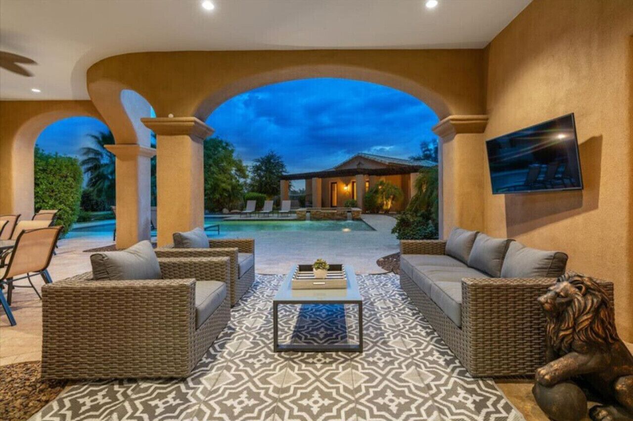An outdoor seating area with wicker furniture, a patterned rug, and a statue of a lion.