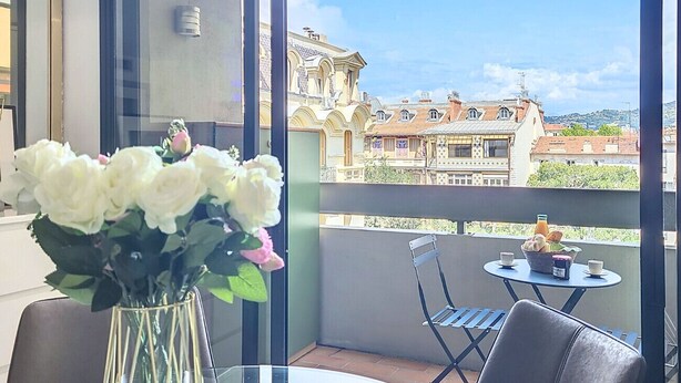 A balcony with a table, chairs, and a vase of flowers. - N&J - POP ART - Central - Balcony (Niza)