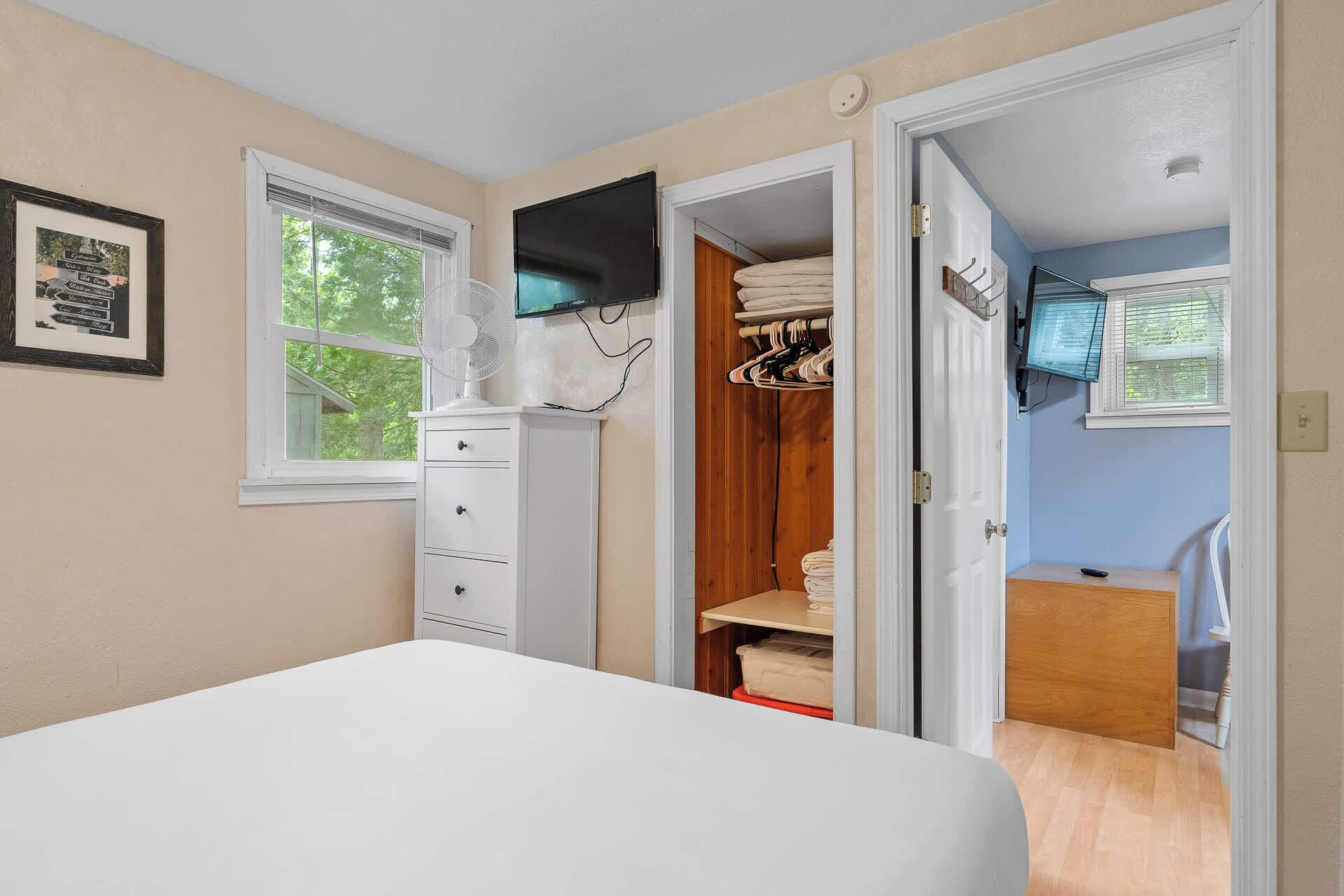 Un dormitorio con una cama, un aparador, un televisor y un armario.