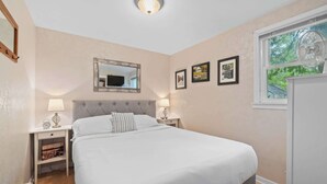 Un dormitorio con cama, mesitas de noche, un espejo y cuadros en la pared.