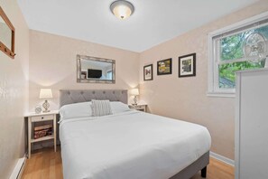 Ein Schlafzimmer mit einem Bett, Nachttischen, einem Spiegel und gerahmten Bildern an der Wand.