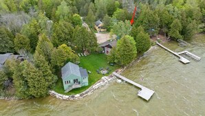 Una propiedad frente al lago con muelle, una casa y un bote.