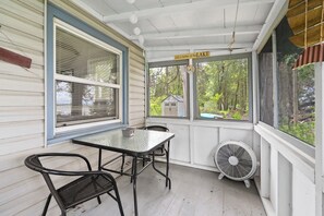 Eine überdachte Veranda mit Tisch und Stühlen, einem Ventilator und einem Schild mit der Aufschrift 'LIFE is better at the LAKE'.