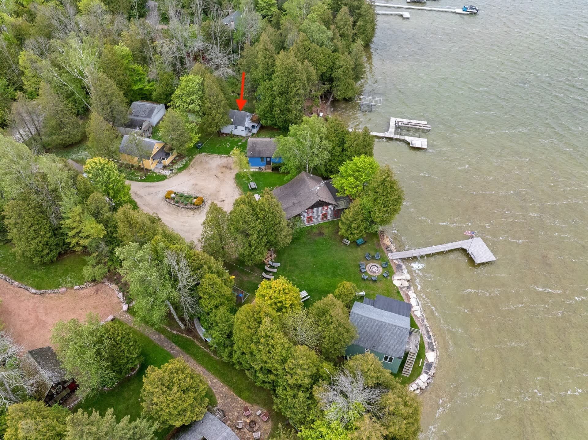 Vista aérea de una propiedad frente al lago con varias casas, un muelle y un bote.