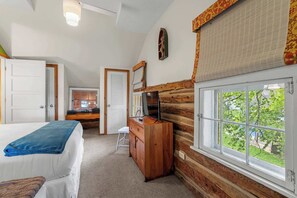 Un dormitorio con cama, cómoda, escritorio, ventana con vistas y puerta.