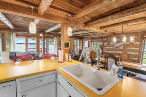 A cabin with a wooden interior, a yellow countertop, a sink, and a view of the lake.