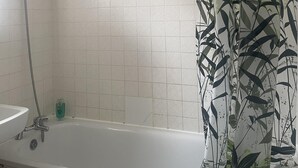 A bathroom with a bathtub, a shower, and a toilet. - Immaculate 3-bed House in Luton (Luton)