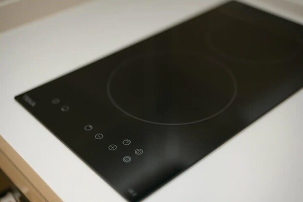 A black induction cooktop with control buttons and a circular cooking area.