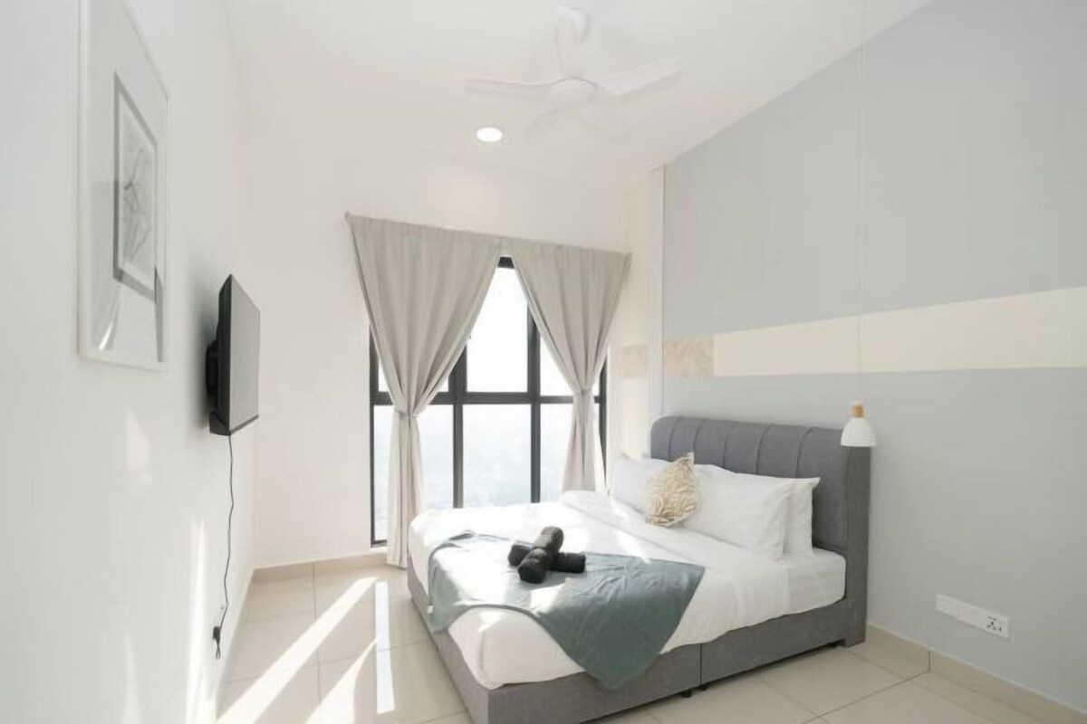 Une chambre à coucher moderne avec un lit, des rideaux, un ventilateur de plafond et un téléviseur fixé au mur.