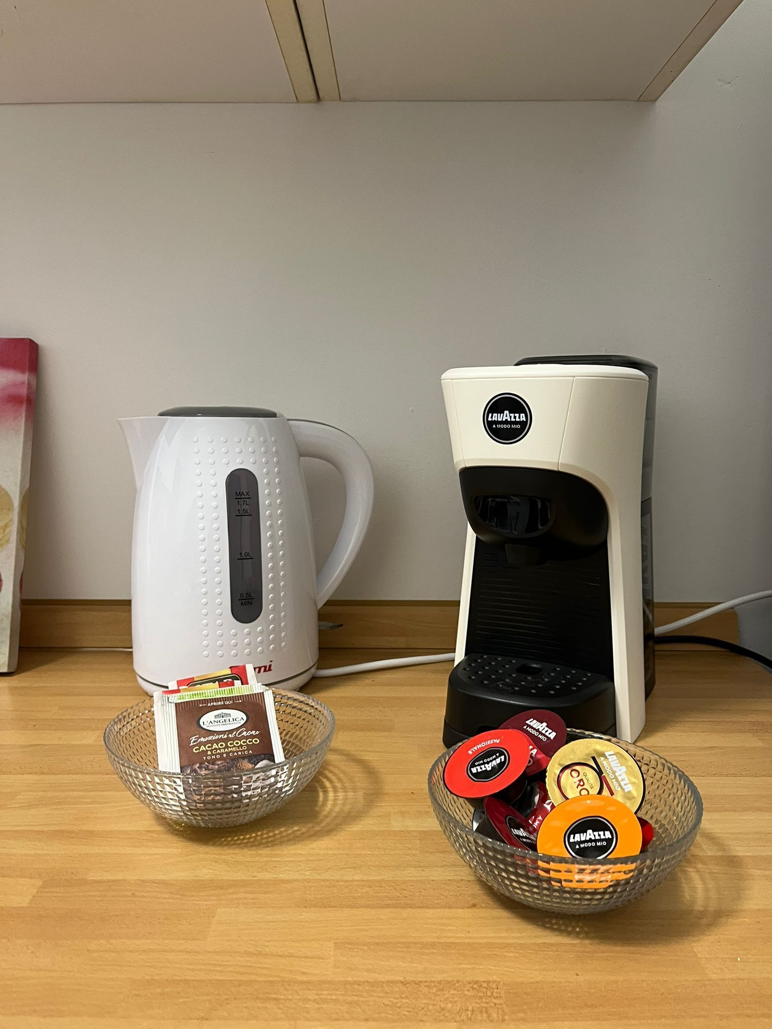 Två kaffemaskiner står på en träyta, och framför varje maskin finns en korg med kaffekapslar.