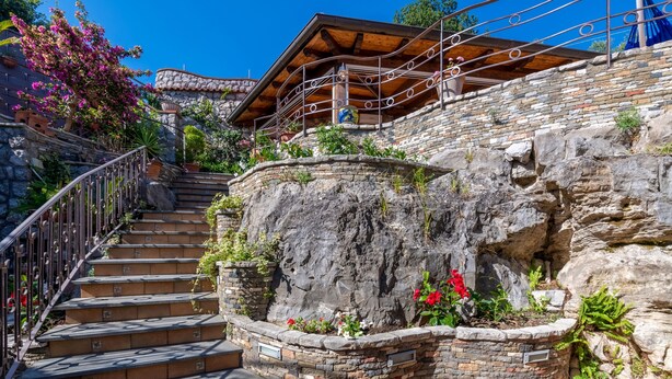 A stone staircase with a metal railing leading to a wooden deck with a blue flag. - Villa Grazielluccia with Sea View and Pool (Priora)