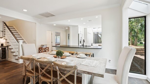 Un espace repas avec une longue table, des chaises en bois et une vue sur l’extérieur grâce à de grandes fenêtres.