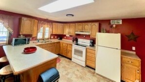Una cocina compacta con armarios de madera, un microondas, una estufa y un refrigerador.