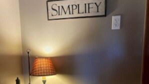 Un rincón con una lámpara de mesa, un barril y un letrero en la pared.