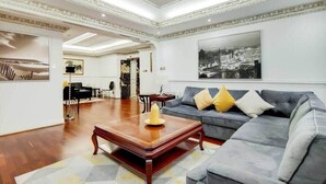 A spacious living room with a grey sofa, a wooden coffee table, and a large framed cityscape picture on the wall. - The Princes Residences (London)