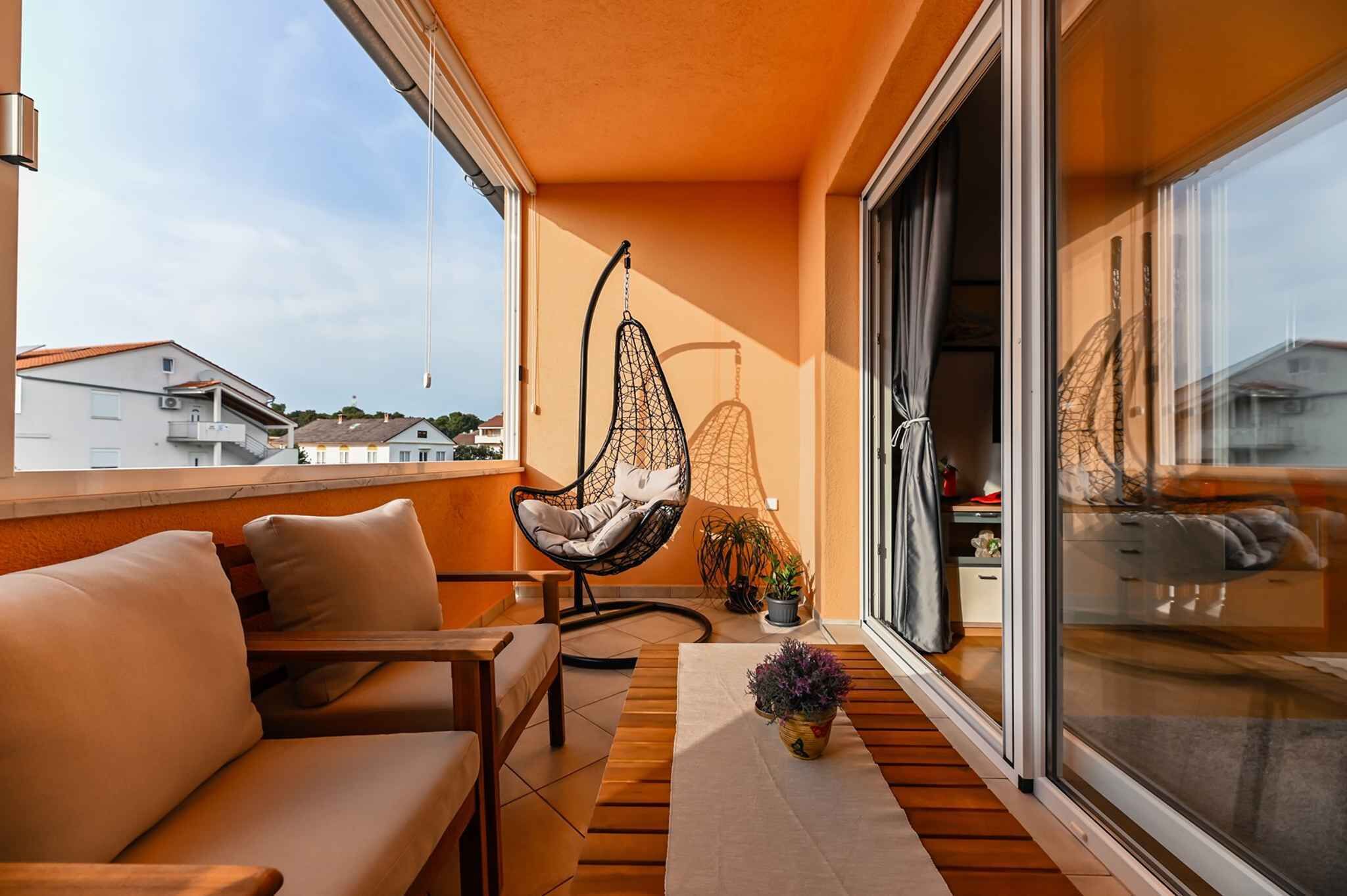 Ein Balkon mit einer Couch, einem Hängesessel und einem Blumentopf.