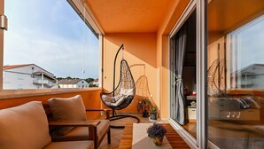 A balcony with a sofa, a hanging chair, and a potted plant. - Holiday apartment with balcony and partial sea view (Biograd na Moru)
