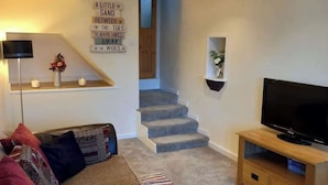 A living room with a sofa, TV, and a staircase. - Cosy one bedroom cottage in Pickering (Pickering)