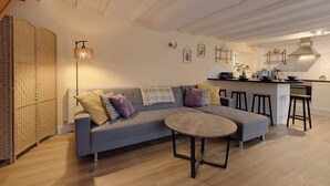 A modern living room with a sofa, round coffee table, and kitchen area with stools. - Lavender Cottage - a beautiful quirky cottage (Snainton)