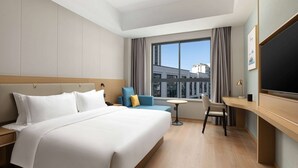 Una habitación de hotel moderna con una cama grande, un escritorio, una silla y un televisor.