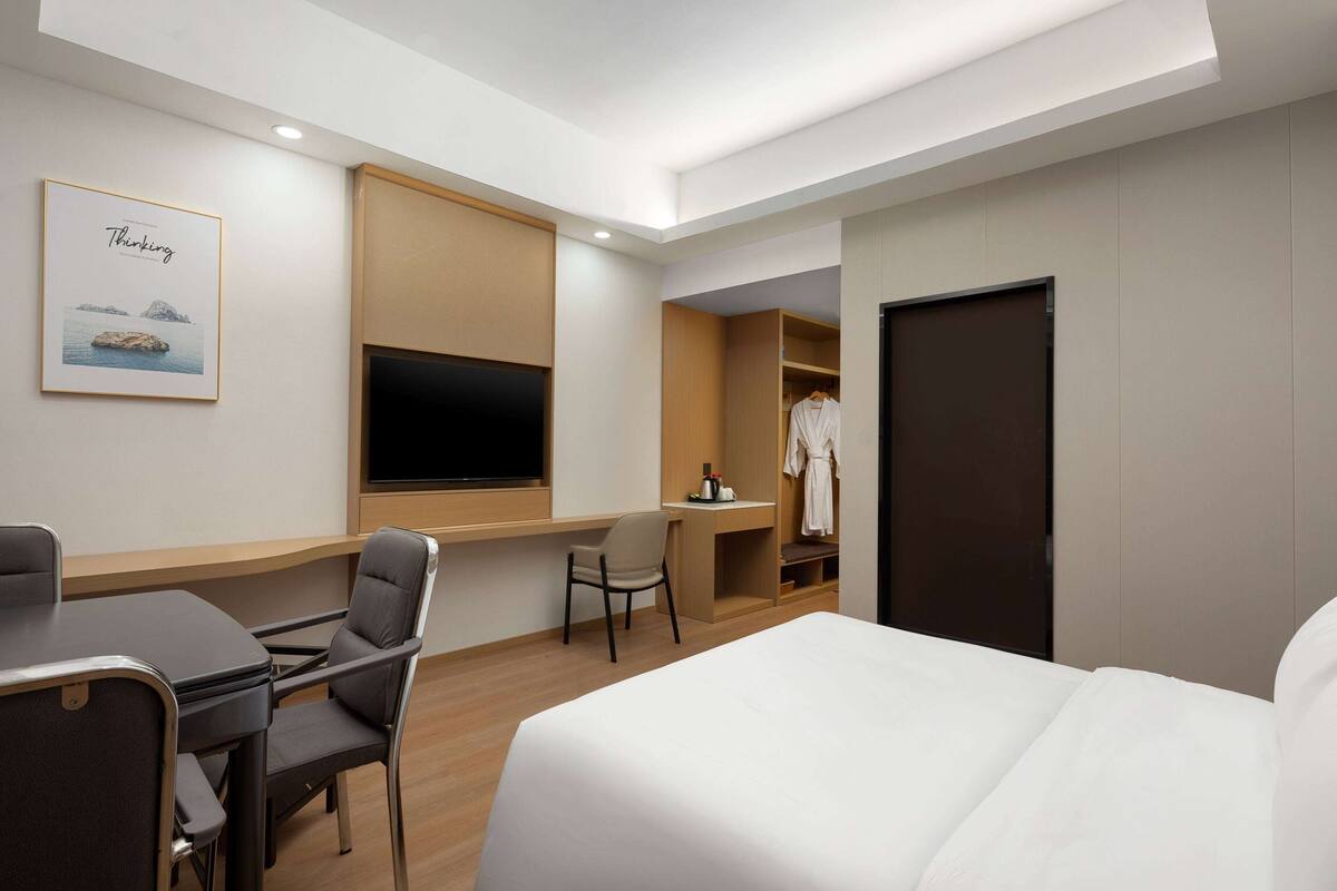 Hotellihuone, jossa on sänky, työpöytä, tuoli, televisio ja vaatekaappi.