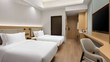 A hotel room with two beds, a desk, a chair, a television, and a door leading to a bathroom.