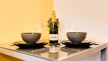 A table with a bottle of champagne, two bowls, and two glasses.