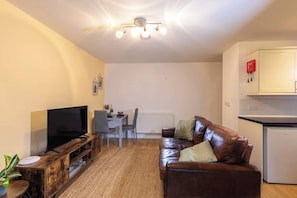Relax in this cozy space with a flat-screen TV, leather sofa, and compact kitchenette.