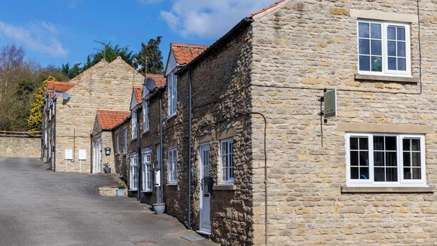 A stone building with a steeply pitched roof, a narrow street, and a clear sky. - Heather Cottage - a beautiful cosy cottage (Snainton)