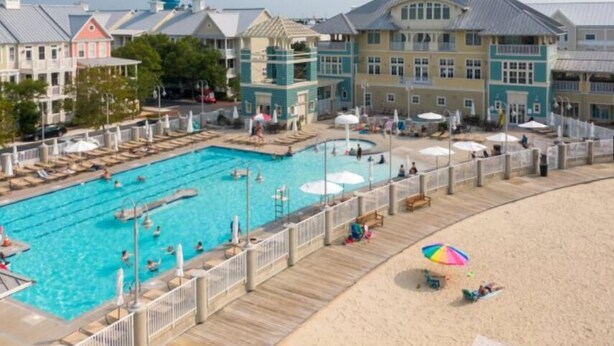 Un complexe hôtelier doté d’une grande piscine, d’une plage et de différents bâtiments aux styles architecturaux variés.