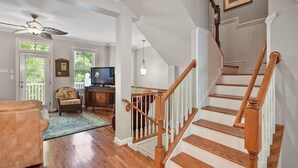Un salon spacieux doté d’un plancher en bois franc, d’un escalier en bois et d’un ventilateur de plafond.