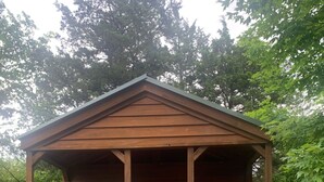 Eine kleine Holzhütte mit roter Tür, einem Fenster und einer Veranda mit Stühlen.
