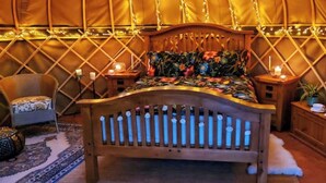 Een gezellige kamer met een houten bed, een stoel, een klein tafeltje en een nachtkastje.