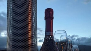 Een fles Rosé Prosecco op een tafel met twee glazen, voor een pittoresk landschap.