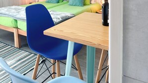 A small, modern room with a bed, a table, and two chairs. - Go4surf Beachlofts (Peniche)