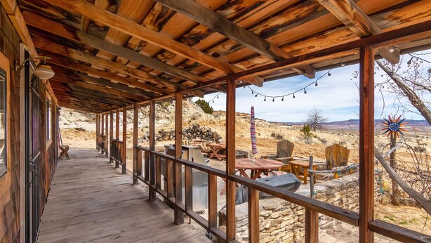 Eine überdachte Holzterrasse mit einer Steinwand und Gartenmöbeln.