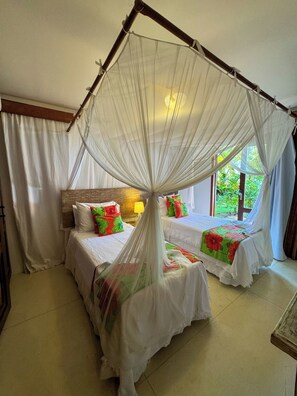A room with two beds, each with a canopy bedspread and pillows with floral patterns. - House with 4 suites, a pool, and views of the ocean and the golf course. Turtle Beach (Trancoso)