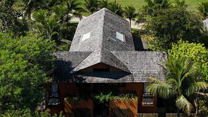 A house with a sloped roof surrounded by lush greenery, overlooking a golf course and the ocean. - House 4 suites, swimming pool, views of the sea and golf course. Turtle Beach  (Trancoso)