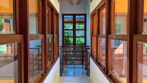 A corridor with wooden-framed windows and a central door leading to a balcony. - House 4 suites, swimming pool, views of the sea and golf course. Turtle Beach  (Trancoso)